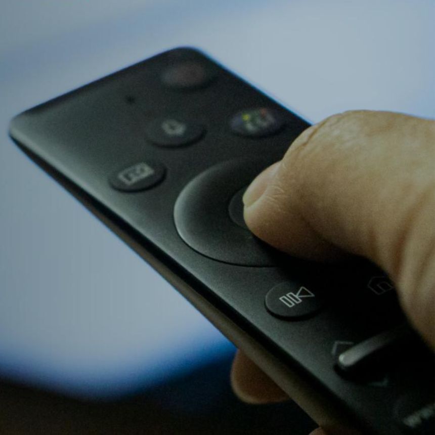 person pushing the main button on a remote control
